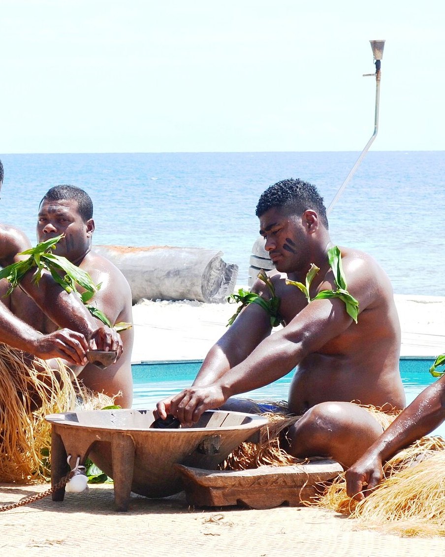 Kava being prepared by hand in a carved wooden tanoa bowl at a Fijian kava ceremony